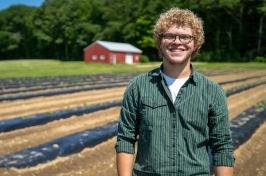 Eliudes Camps Marcano, an exchange student from Puerto Rico, stands in a field at the Kingman Research Farm, 去年夏天，他在那里帮助支持联合国大学的农业研究.